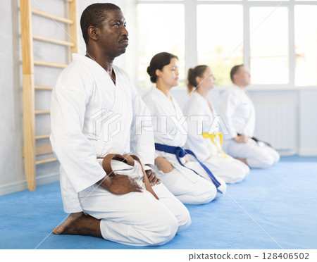 Group of karatekas sitting in pose on floor 128406502