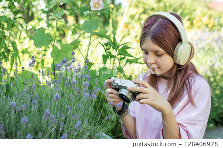 Young photographer taking pictures of lavender flowers in a garden while listening to music 128406978