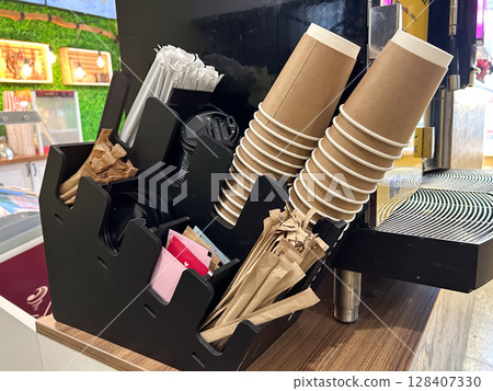 Disposable coffee cups and accessories on a counter holder. 128407330