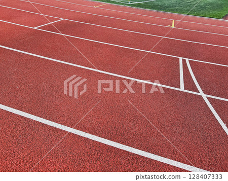 Empty red running track with white lines suggesting movement. Empty red running track with white lines suggesting movement. 128407333