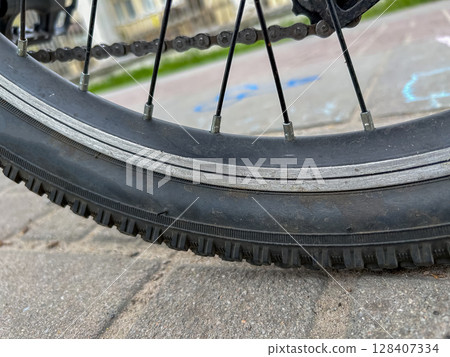 Close-up of a bicycle wheel on a pavement. Close-up of a bicycle wheel on a pavement. 128407334