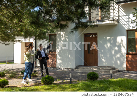 Agent showing house entrance to clients in suburban setting Agent showing house entrance to clients in suburban setting 128407554