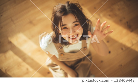 A smiling young woman waving her hand, seen from above | Smile, Aerial view, Greeting 128409442