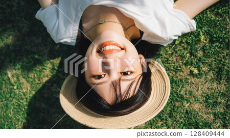 Aerial view of a smiling woman lying on the grass with a summer hat | Smile, Summer, Nature 128409444