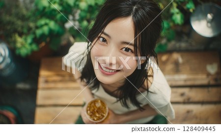 A smiling woman holding a drink in a garden seen from above | Smile, Garden, Drink 128409445