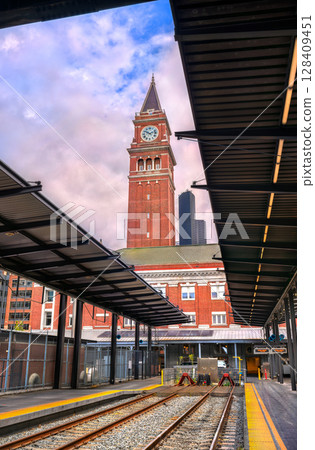 View of Seattle's historic King Street Station under a dramatic sky, showcasing its iconic clock tower rising above train tracks and platform roofs View of Seattle's historic King Street Station under a dramatic sky, showcasing its iconic clock tower rising above train tracks and platform roofs 128409451