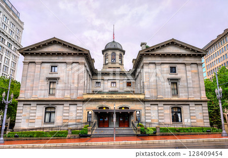 Frontal view of the historic Pioneer Courthouse in Portland, Oregon, showcasing its neoclassical stone facade, columned entry, and central cupola beneath an overcast sky. Frontal view of the historic Pioneer Courthouse in Portland, Oregon, showcasing its neoclassical stone facade, columned entry, and central cupola beneath an overcast sky. 128409454