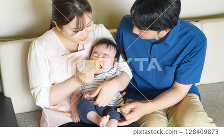 一名男子和一名婦女用奶瓶餵食嬰兒 一名男子和一名婦女用奶瓶餵食嬰兒 128409873