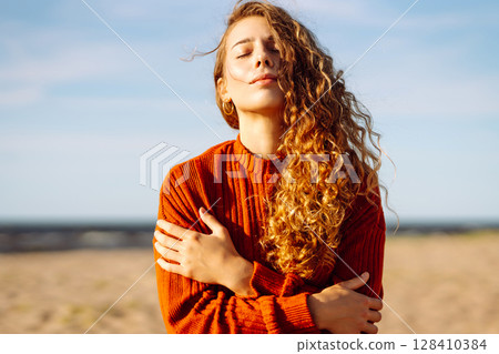 Outdoor portrait of pretty woman on the beach in cold sunny weather. Travel, fashion, blogging 128410384