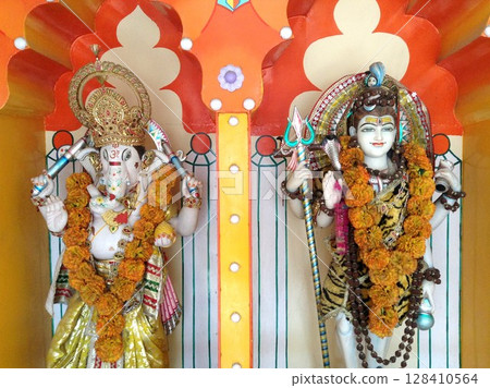 Lord Ganesha and Lord Shiva statues decorated with flower garlands in hindu temple in Rishikesh, India. 128410564