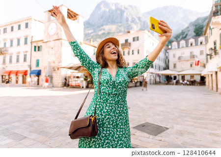 Happy woman takes a selfie photo on smartphone against the background of old city. Travel and life 128410644