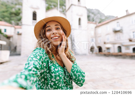 Selfie while traveling. Young woman takes selfie photo on a smartphone. Lifestyle, travel, tourism 128410696
