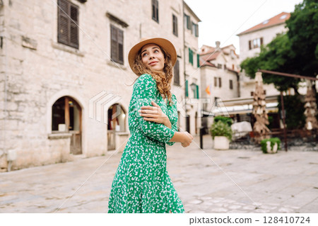 Happy female tourist in beautiful dress walking in the street of the city. Fashion style. Travel. 128410724