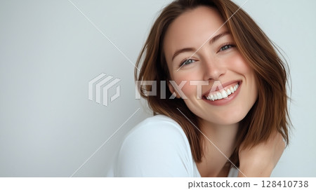 Smiling Woman With Shoulder-Length Hair Poses Against a Neutral Background, Showcasing a Joyful Expression 128410738
