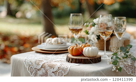 Charming autumn wedding table setting showcases pumpkins, candles, and wine glasses, creating a cozy, inviting atmosphere for guests 128411390