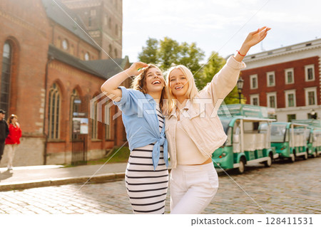 Female tourists in bright dress enjoys sights of city on sunny day. Concept of lifestyle, fashion. Female tourists in bright dress enjoys sights of city on sunny day. Concept of lifestyle, fashion. 128411531