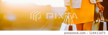 Young woman with shopping bags walking on street. Female coming from a sale downtown 128411873