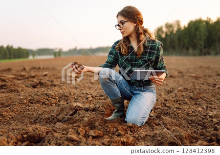 Young woman agronomist checks the quality of the soil before sowing. Concept of technology, ecology. 128412398