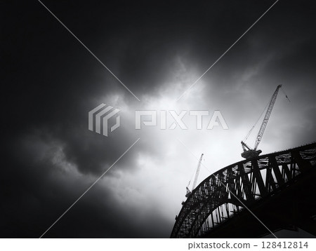 Dramatic black and white shot of a colossal bridge silhouette against a stormy sky. Evokes themes of industry, strength, and overcoming adversity. 128412814