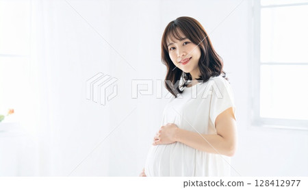 白色房間裡一位身穿白色衣服的長髮孕婦的畫像 128412977