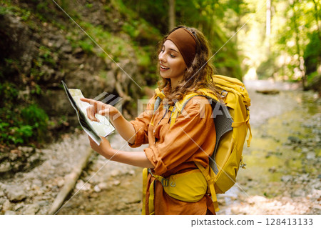 Young woman on a mountain path with a map in her hands, exploring hiking trails. Adventure concept. Young woman on a mountain path with a map in her hands, exploring hiking trails. Adventure concept. 128413133