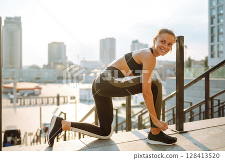 Young woman getting ready for jogging outdoors while lacing her sneakers. Health and sport concept. Young woman getting ready for jogging outdoors while lacing her sneakers. Health and sport concept. 128413520