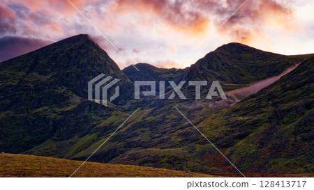 Peaceful highland scene at sunset. The mountains stand tall under a vibrant, colorful sky. Nature's beauty captured. Peaceful highland scene at sunset. The mountains stand tall under a vibrant, colorful sky. Nature's beauty captured. 128413717