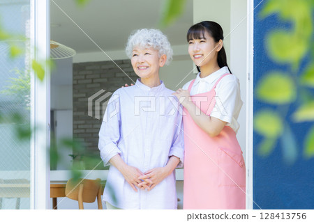 A female caregiver caring for a senior woman in the living room 128413756
