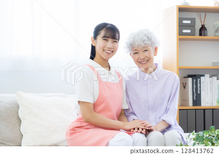 A female caregiver caring for a senior woman in the living room A female caregiver caring for a senior woman in the living room 128413762