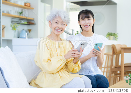 Senior woman looking at smartphone in living room 128413798