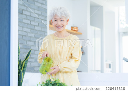 Senior woman watering houseplants 128413818