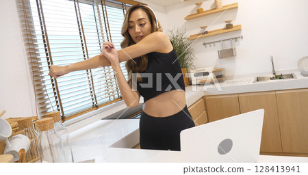 Young Sport Women look at laptop online trainer home fitness workout exercise in living room. Woman using laptop on floor in sportswear arms stretching body weight traning. Healthy lifestyle concept 128413941