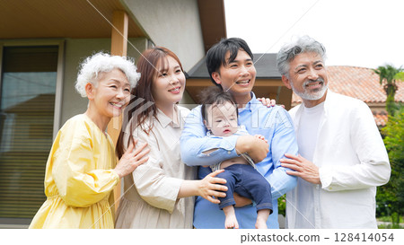 Smiling three-generation family surrounding a baby 128414054