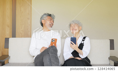 Senior couple laughing together while looking at a smartphone 128414065