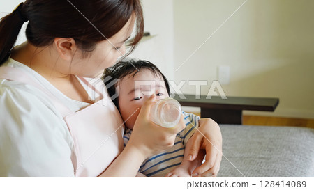 一位婦女用奶瓶餵養嬰兒 128414089