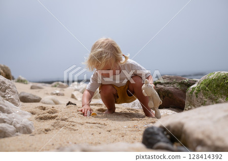 4-year-old European girl searching for seashells on the beach 128414392