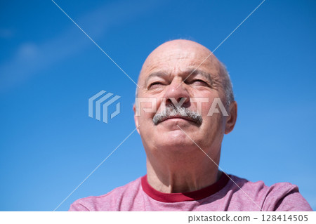 Elderly Spanish Man Against Blue Sky, Slightly Sad and Frowning 128414505