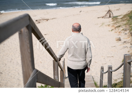 An elderly Spanish pensioner walks down the stairs to the beach 128414534