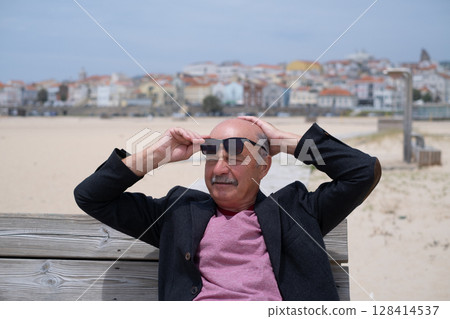 Elderly Man Sitting on Bench on Beach and Relaxing during Vacation in Portugal 128414537