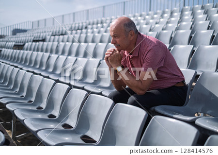 Elderly Spanish Man Sitting Alone on Stadium Stands Feeling Sad 128414576