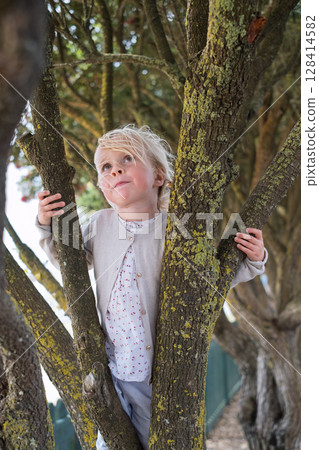 European Blonde Girl Climbing a Tree 128414582