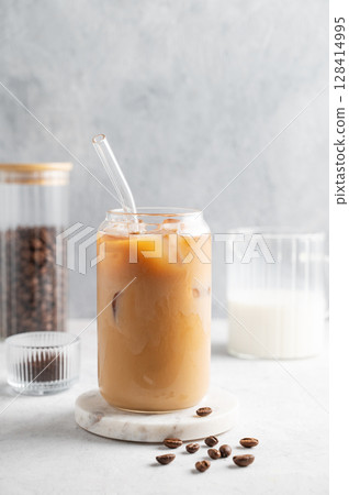 Ice latte coffee in a glass with milk on a marble board on a  light background with coffee beans. 128414995