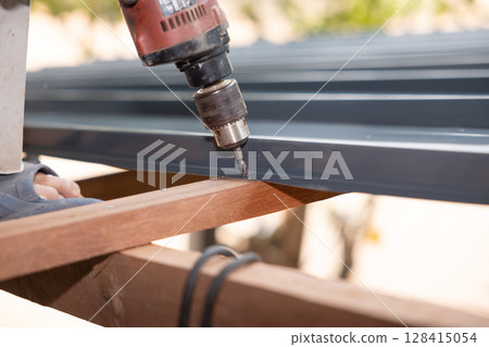 Auger power tool in roof construction. Auger power tool in roof construction. 128415054