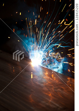 Welder uses torch to make sparks during manufacture of metal equipment, industrial professional worker Welder uses torch to make sparks during manufacture of metal equipment, industrial professional worker 128415209