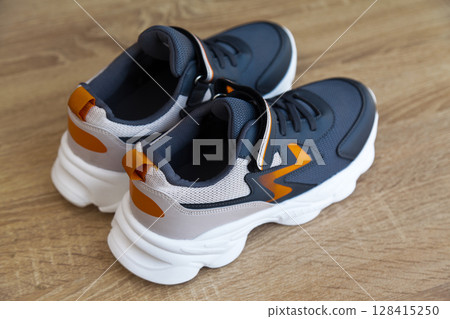 Stylish comfortable and useful grey or blue orange sneakers, on oak wooden floor Stylish comfortable and useful grey or blue orange sneakers, on oak wooden floor 128415250