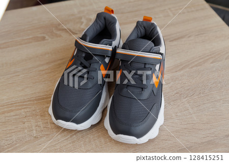 Stylish comfortable and useful grey or blue orange sneakers, on oak wooden floor Stylish comfortable and useful grey or blue orange sneakers, on oak wooden floor 128415251