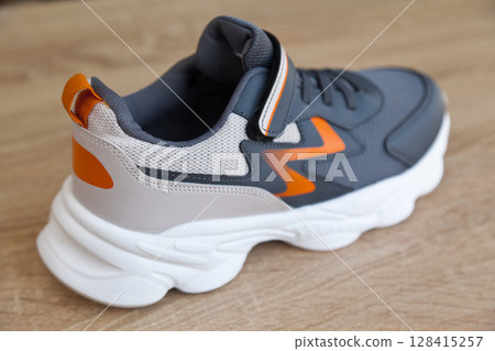 Stylish comfortable and useful grey or blue orange sneakers, on oak wooden floor Stylish comfortable and useful grey or blue orange sneakers, on oak wooden floor 128415257