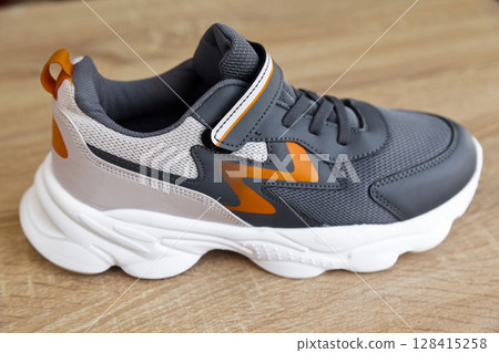 Stylish comfortable and useful grey or blue orange sneakers, on oak wooden floor Stylish comfortable and useful grey or blue orange sneakers, on oak wooden floor 128415258