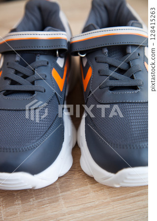 Stylish comfortable and useful grey or blue orange sneakers, on oak wooden floor Stylish comfortable and useful grey or blue orange sneakers, on oak wooden floor 128415263