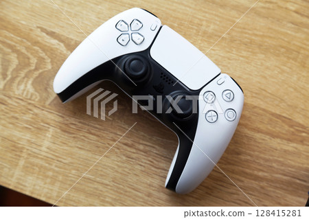 Sony PS5 Wireless Controller, on an oak wooden table, PlayStation is a video gaming brand that consists of five home video game consoles. Istanbul Turkey May 01 2025 Sony PS5 Wireless Controller, on an oak wooden table, PlayStation is a video gaming brand that consists of five home video game consoles. Istanbul Turkey May 01 2025 128415281